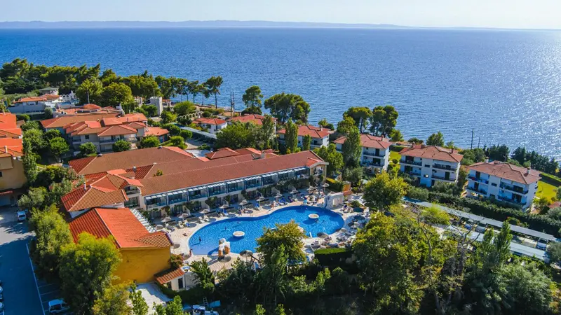 Vue aérienne d'un complexe hôtelier avec piscine et végétation luxuriante surplombant la mer.