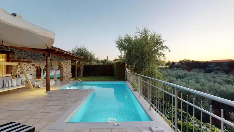 Une piscine rectangulaire avec une terrasse ensoleillée et une vue sur un paysage verdoyant.