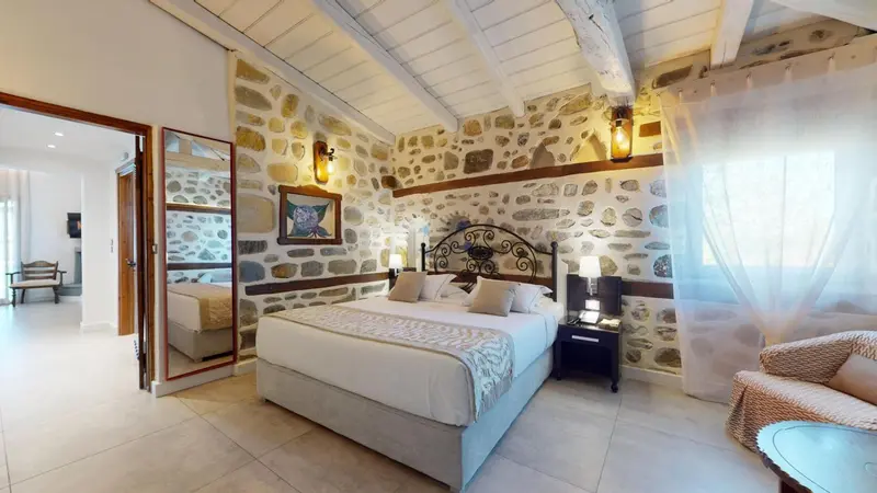 Une chambre lumineuse avec un lit à baldaquin et un mur en pierre.