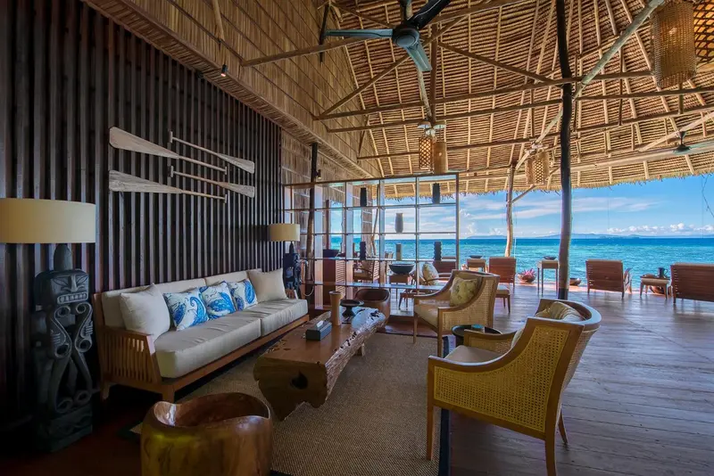 Espace de détente intérieur avec canapés et fauteuils en bois.
