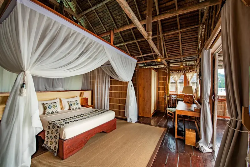 Une chambre avec un lit à baldaquin et un bureau en bois.