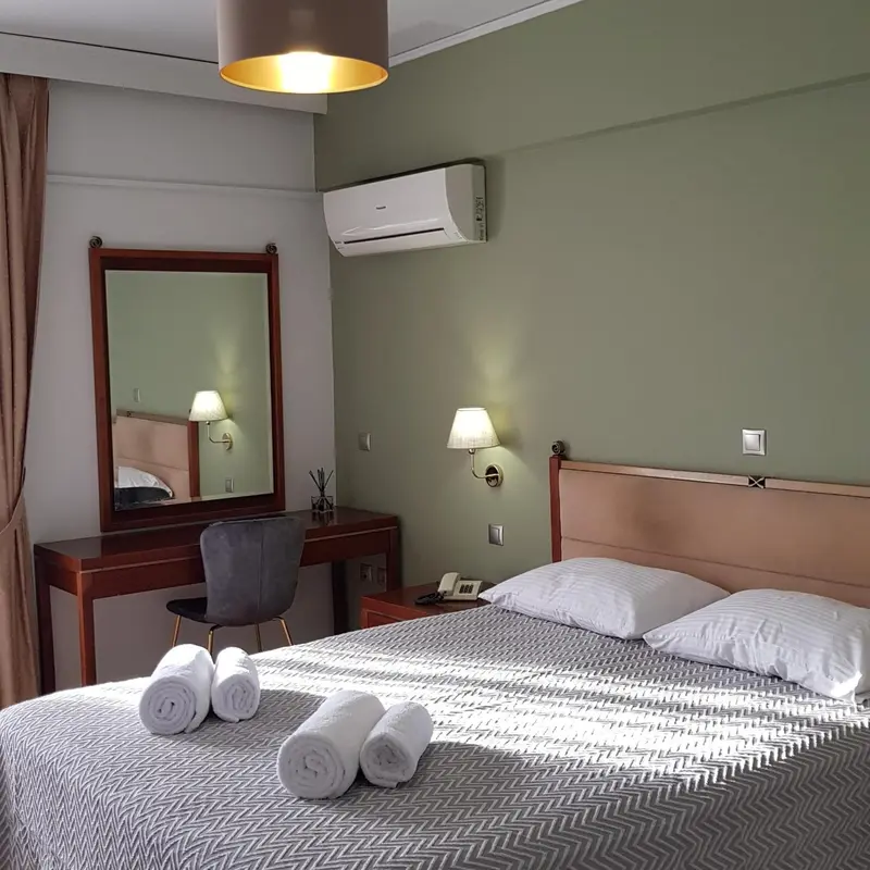 Une chambre d'hôtel lumineuse avec un lit et un coin coiffeuse.