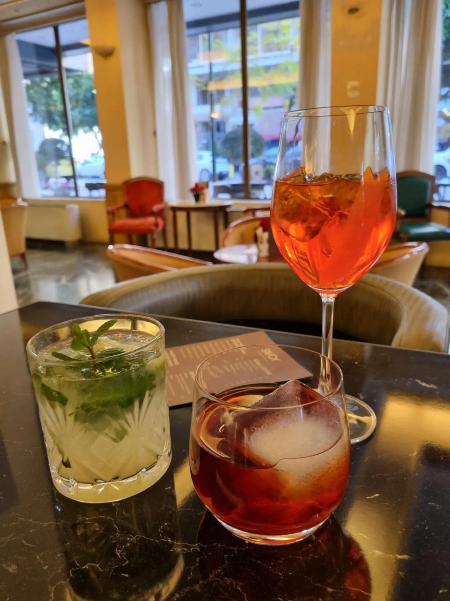 Deux verres de cocktails colorés sur une table sombre dans un espace lumineux.