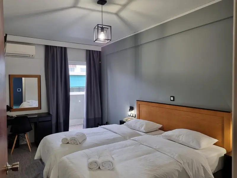 Une chambre avec deux lits simples et un miroir mural.