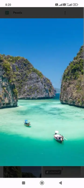 Vue aérienne d'une baie turquoise encadrée de falaises verdoyantes.