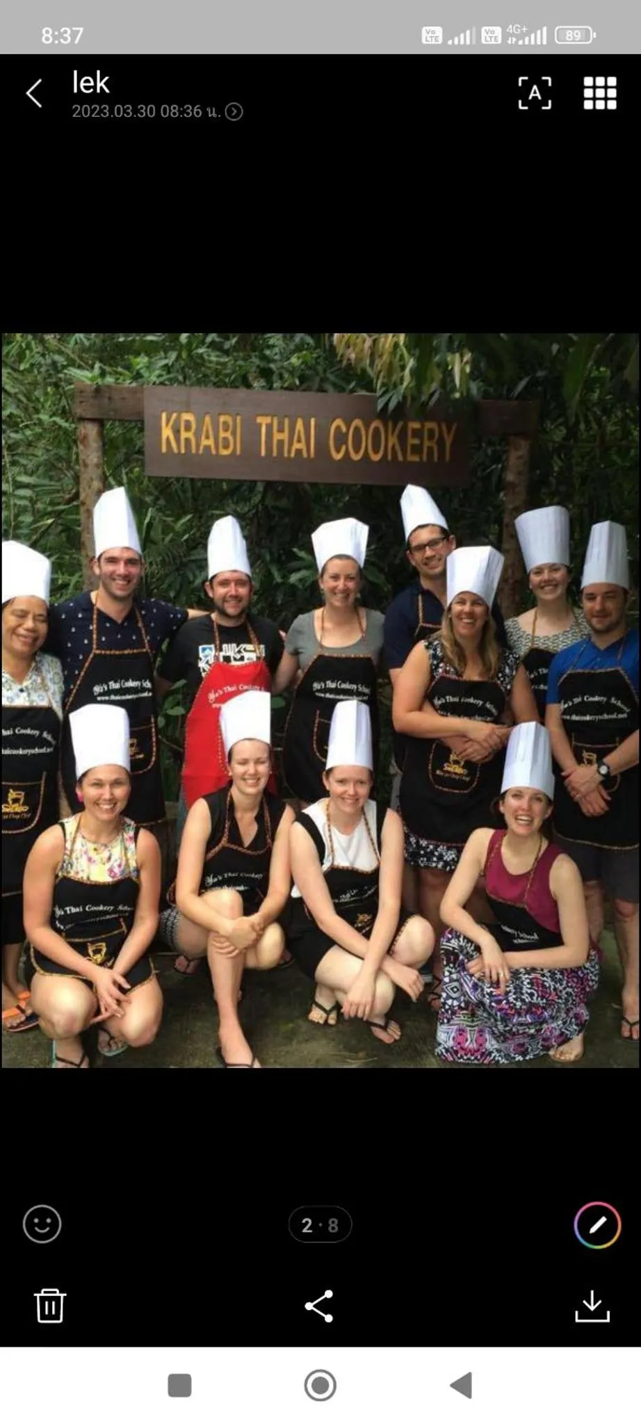 Groupe de personnes souriantes portant des toques de chef et des tabliers devant une enseigne.