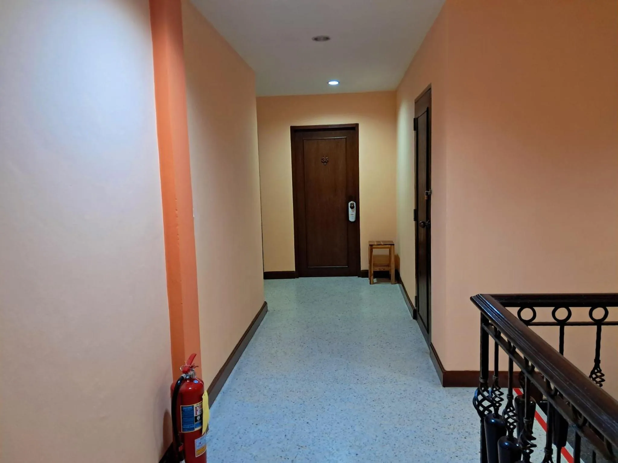 Couloir d'hôtel avec portes en bois et éclairage artificiel.