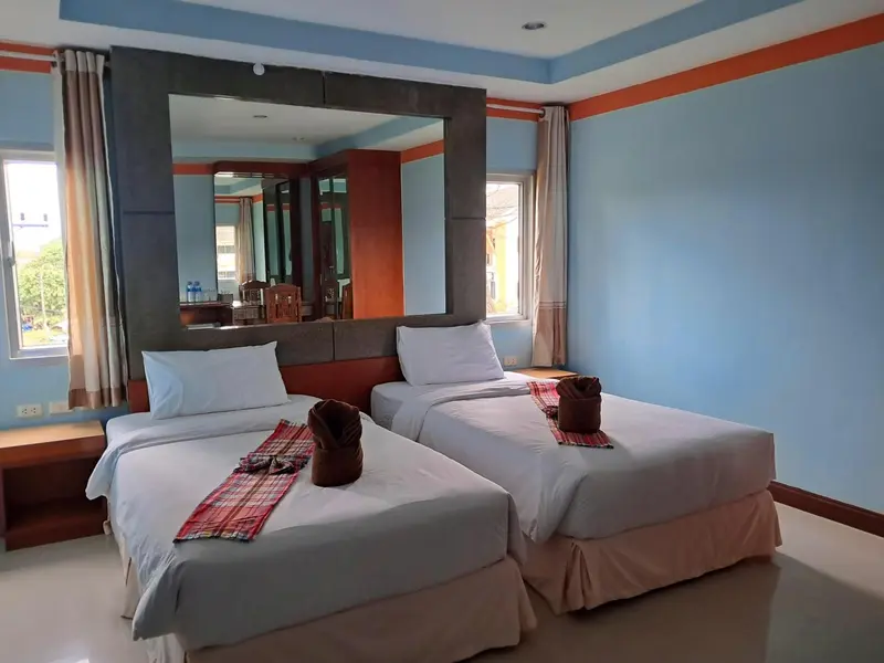 Une chambre lumineuse avec deux lits simples et un grand miroir.