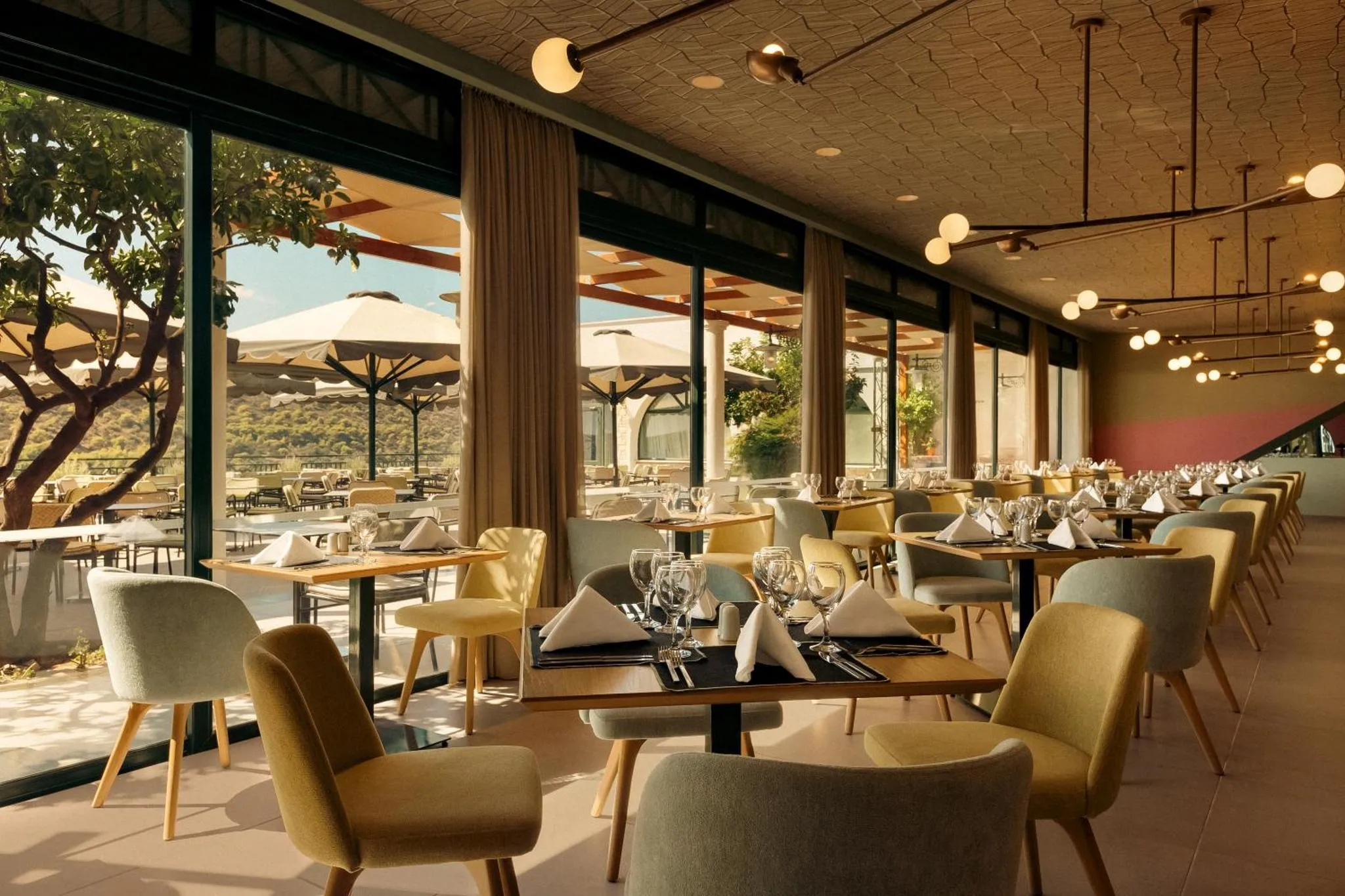 Une salle de restaurant lumineuse avec des tables dressées et de grandes baies vitrées donnant sur une terrasse.