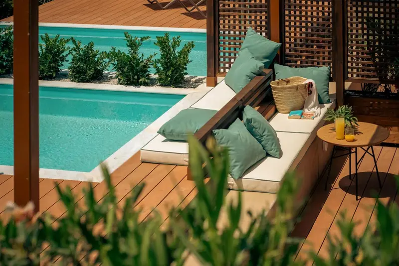 Espace de détente extérieur avec canapés et piscine turquoise.