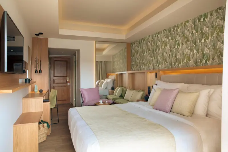 Chambre lumineuse avec un grand lit et un mur décoratif.