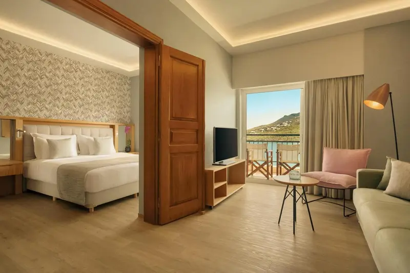 Une chambre lumineuse s'ouvre sur un espace de détente avec canapé et balcon.