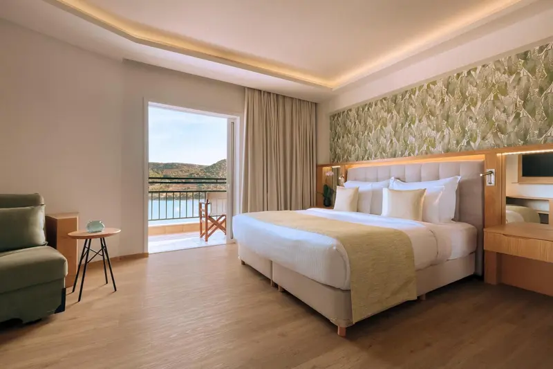 Une chambre lumineuse avec un grand lit et un accès à un balcon.