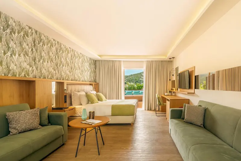 Chambre lumineuse avec un grand lit et un espace salon.