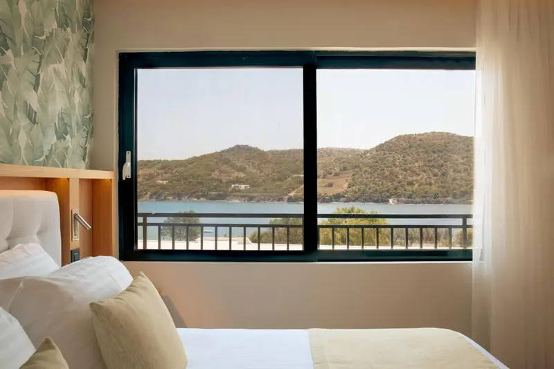 Une chambre lumineuse offre une vue sur la mer et les collines environnantes.