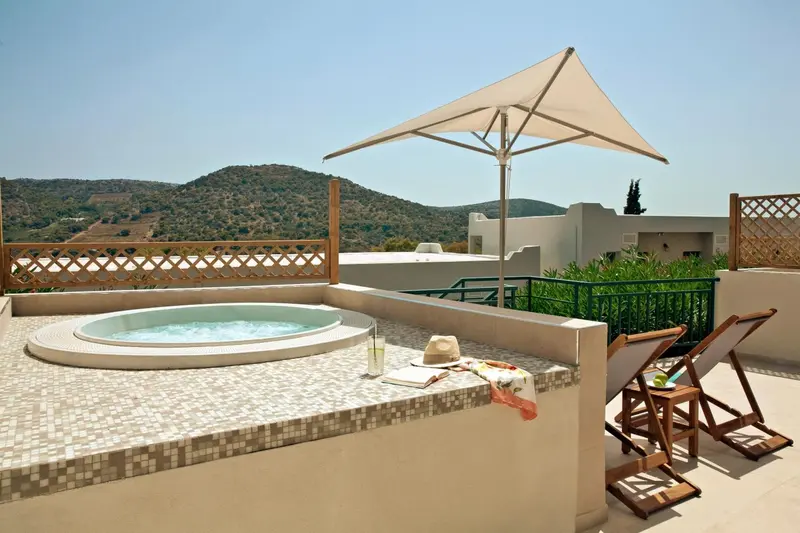 Un jacuzzi sur une terrasse avec des chaises longues et une vue sur les collines.
