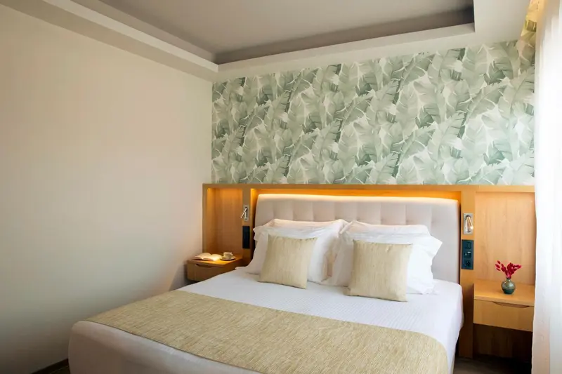 Une chambre lumineuse avec un grand lit recouvert d'oreillers et d'une courtepointe.