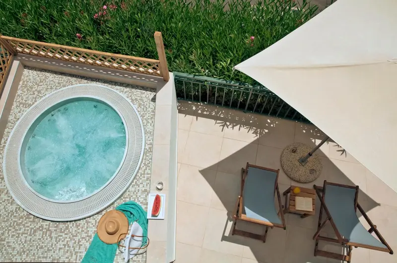 Jacuzzi et chaises longues sur une terrasse ensoleillée.