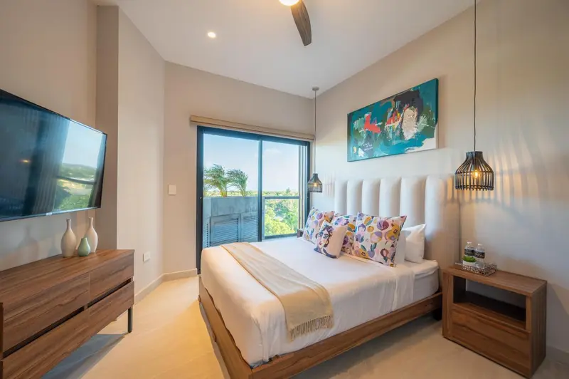 Une chambre lumineuse avec un grand lit et un accès à une vue extérieure.