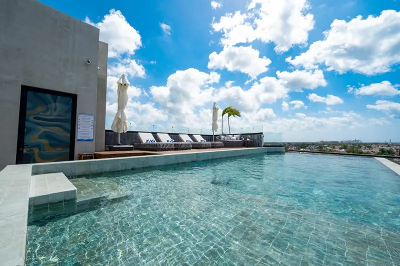 Piscine à débordement sur un toit-terrasse ensoleillé avec transats.