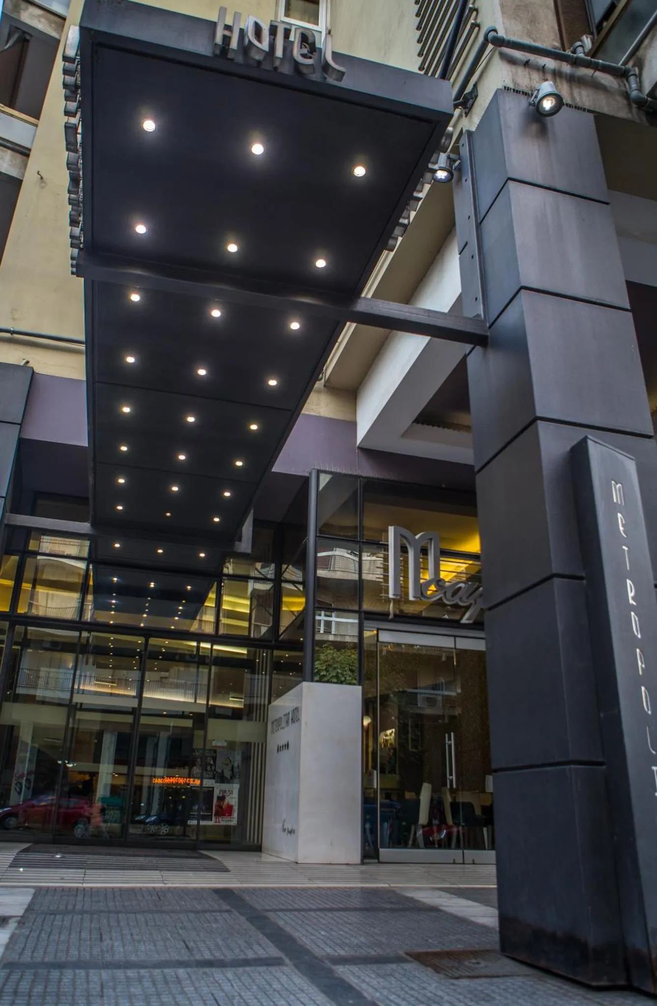 L'entrée d'un hôtel moderne avec un auvent sombre et des vitrines.