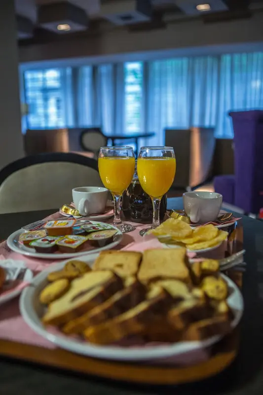 Un plateau de petit-déjeuner avec des viennoiseries, des jus d'orange et des confitures est présenté sur une table.