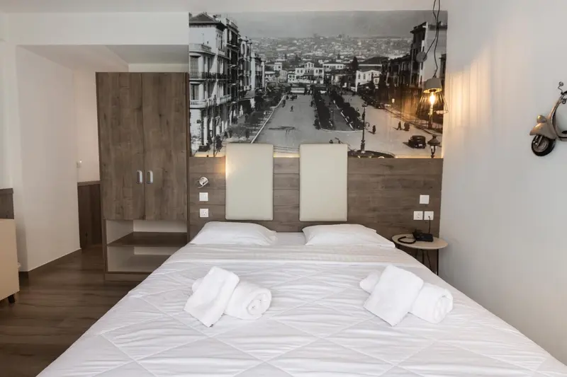 Une chambre avec un grand lit et une décoration murale représentant une rue de ville.
