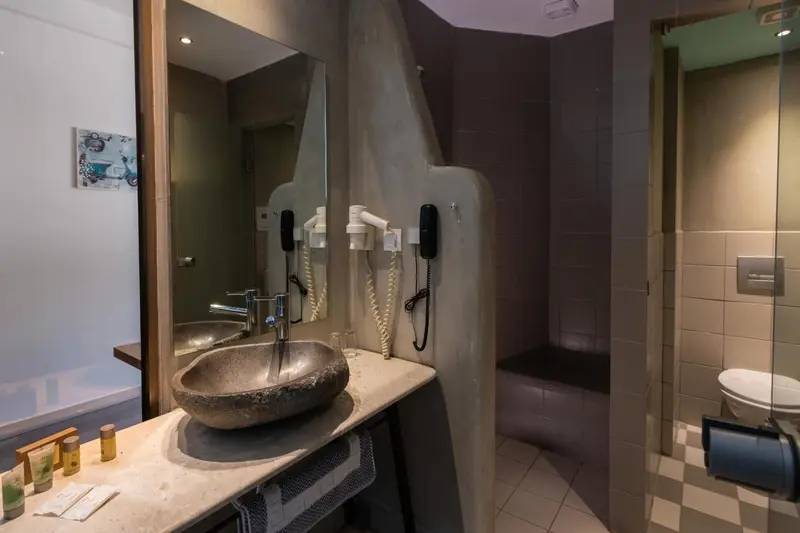 Une salle de bain avec lavabo en pierre et douche à l'italienne.