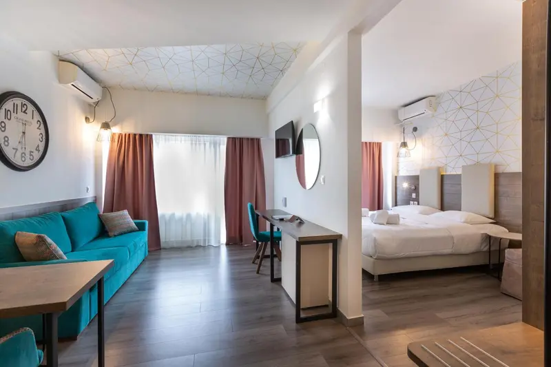 Espace de vie lumineux avec canapé turquoise et lit double.