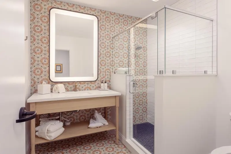 Une salle de bain lumineuse avec une douche vitrée et un meuble vasque en bois.