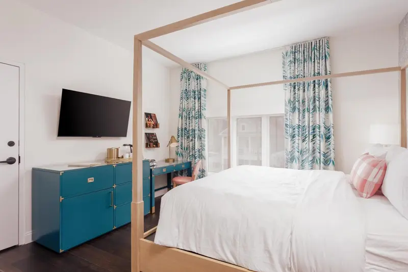 Une chambre lumineuse avec un grand lit à baldaquin et un bureau.