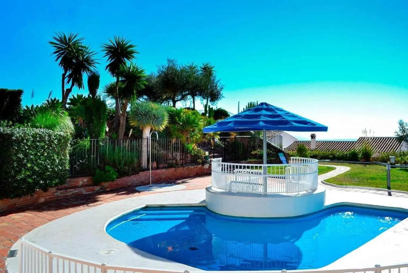 Une piscine avec un espace de détente ombragé et une végétation luxuriante.