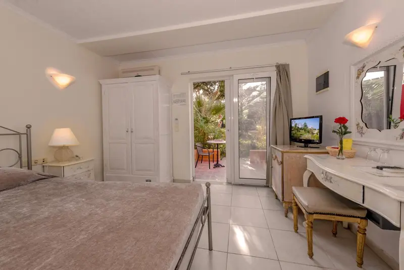 Une chambre lumineuse avec un lit et un coin coiffure donnant sur une terrasse.
