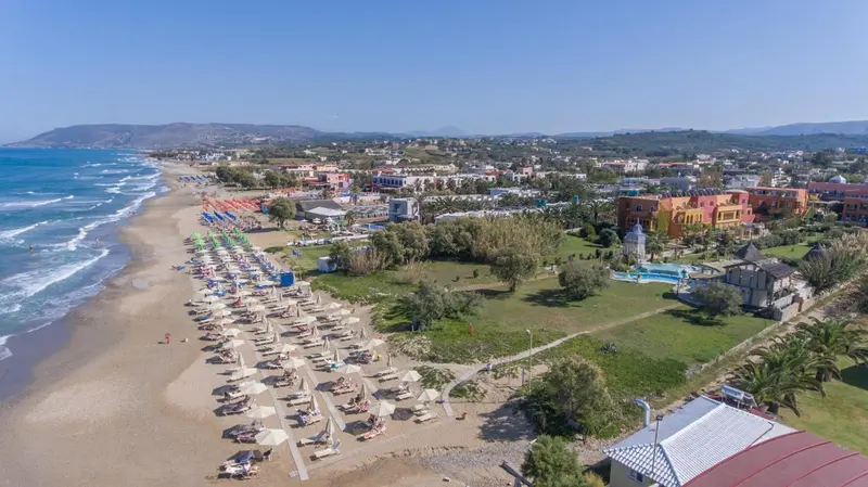 Vue aérienne d'une plage avec transats et parasols devant un ensemble hôtelier.