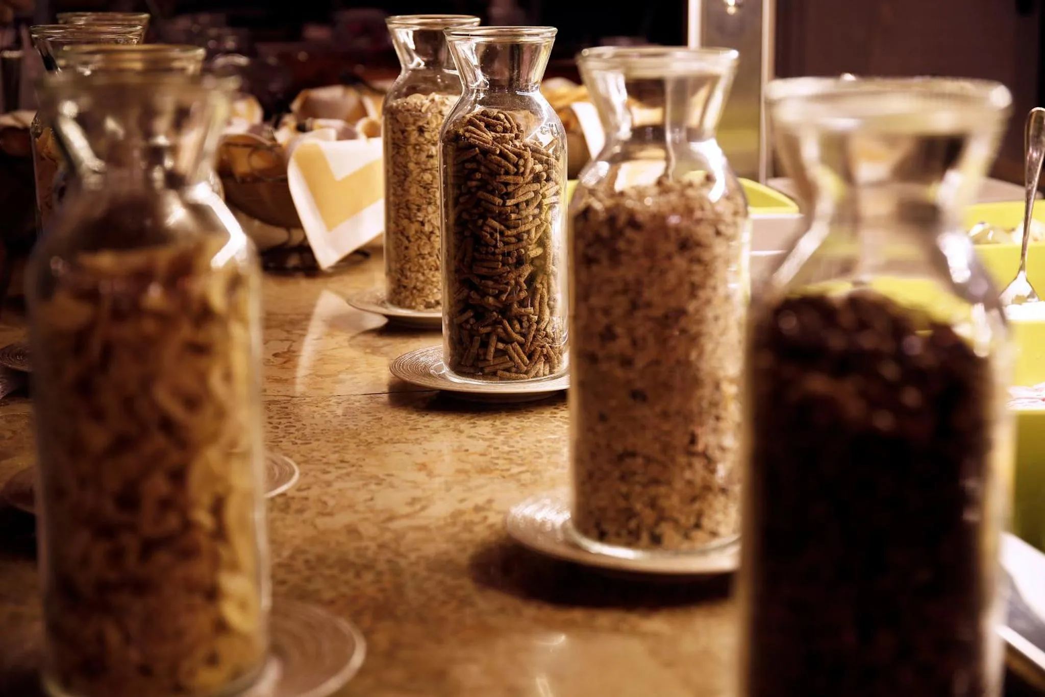 Des bocaux en verre remplis de céréales et de graines sont alignés sur un comptoir.