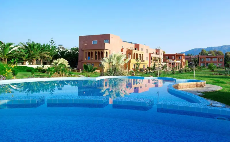 Vue d'un complexe hôtelier avec une piscine sinueuse et une végétation luxuriante.