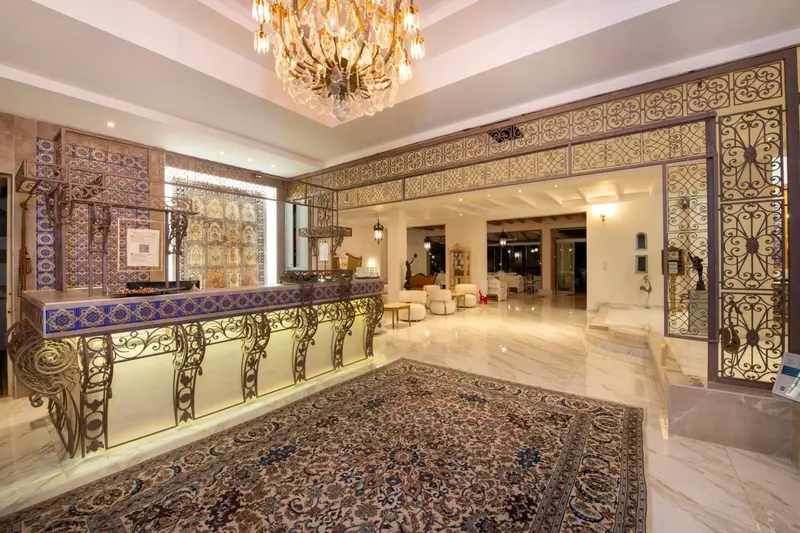 Hall d'accueil lumineux avec un comptoir de réception décoré et un tapis oriental.