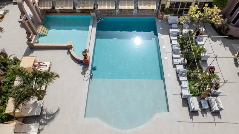 Vue aérienne d'une piscine rectangulaire entourée d'un solarium aménagé de transats.