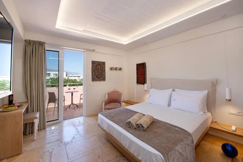 Chambre lumineuse avec un lit double et un accès à un balcon.