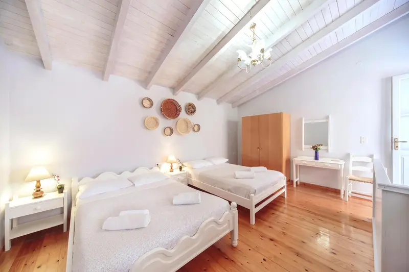 Chambre lumineuse avec deux lits simples et décoration murale.