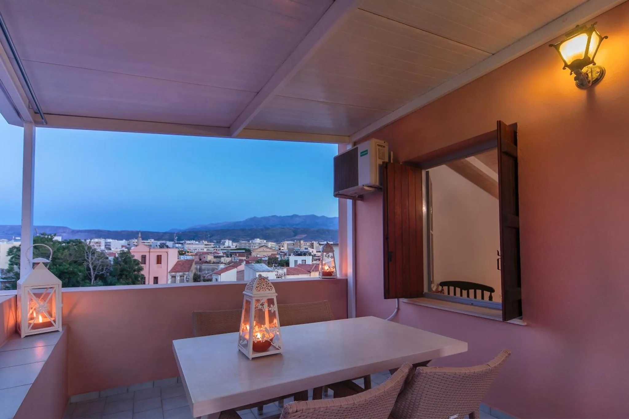Terrasse avec mobilier et vue sur la ville au crépuscule.