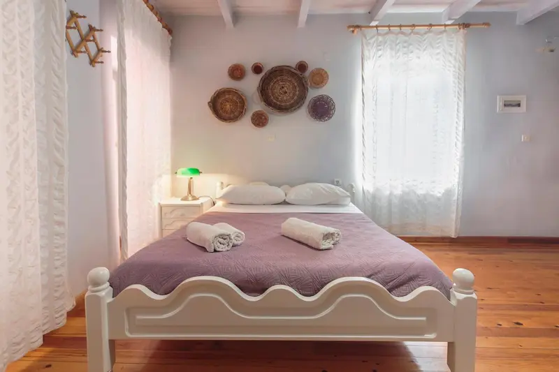 Une chambre lumineuse avec un lit recouvert d'une courtepointe violette et de serviettes.