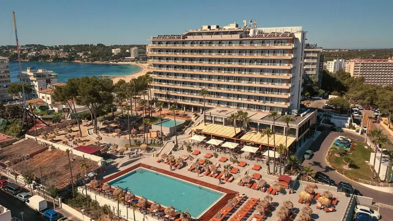 Vue aérienne d'un bâtiment blanc avec des balcons et une piscine en contrebas.