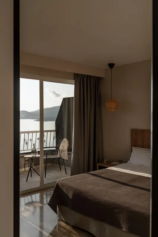 Une chambre lumineuse s'ouvre sur une terrasse avec vue sur la mer.