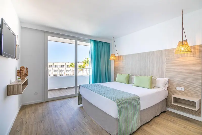 Chambre lumineuse avec un grand lit et un accès à une terrasse.