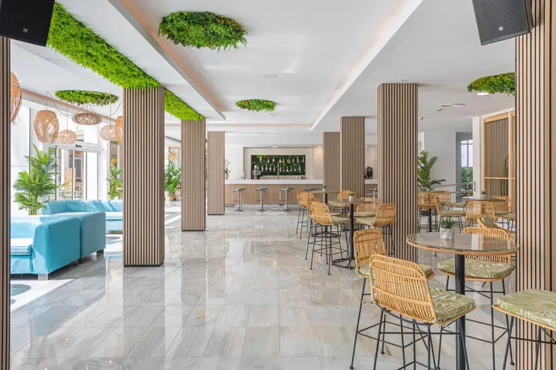 Espace lumineux avec canapés bleus, tables et chaises en rotin.