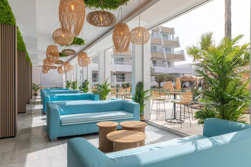 Espace de détente intérieur avec canapés turquoise et luminaires en rotin.