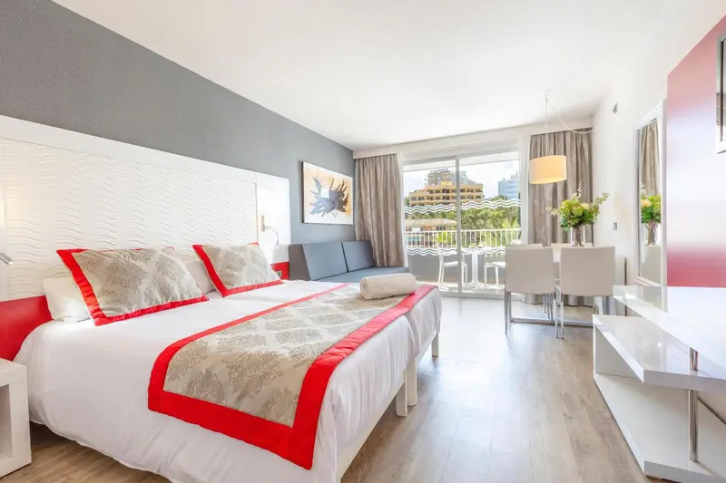 Une chambre lumineuse avec un grand lit et un espace repas.