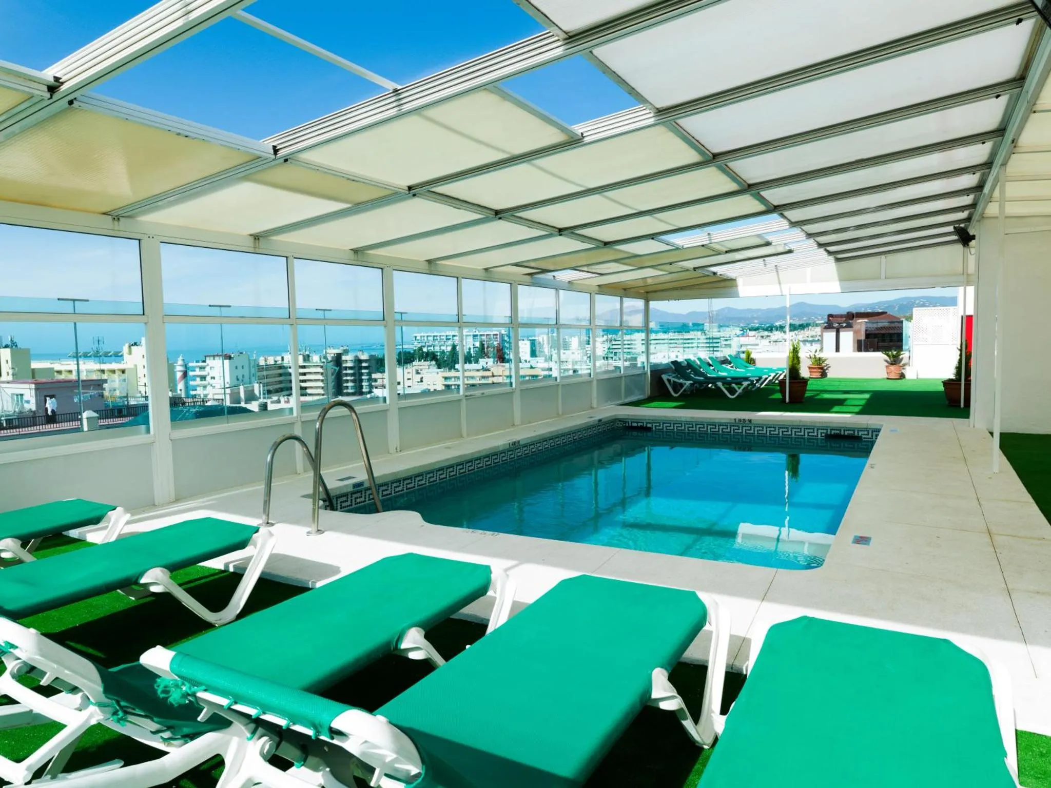 Terrasse avec piscine et chaises longues face à la mer.