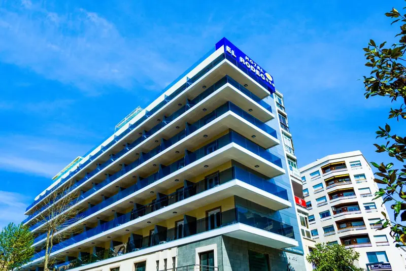 Façade moderne d'un bâtiment avec de larges baies vitrées et des balcons.